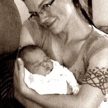 Lyssa smiling with glasses holding baby.