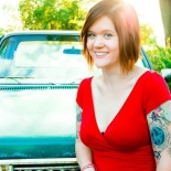 Kaity wearing red shirt sitting in front of car