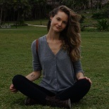 Photo of Carlyn, sitting cross-legged in the grass